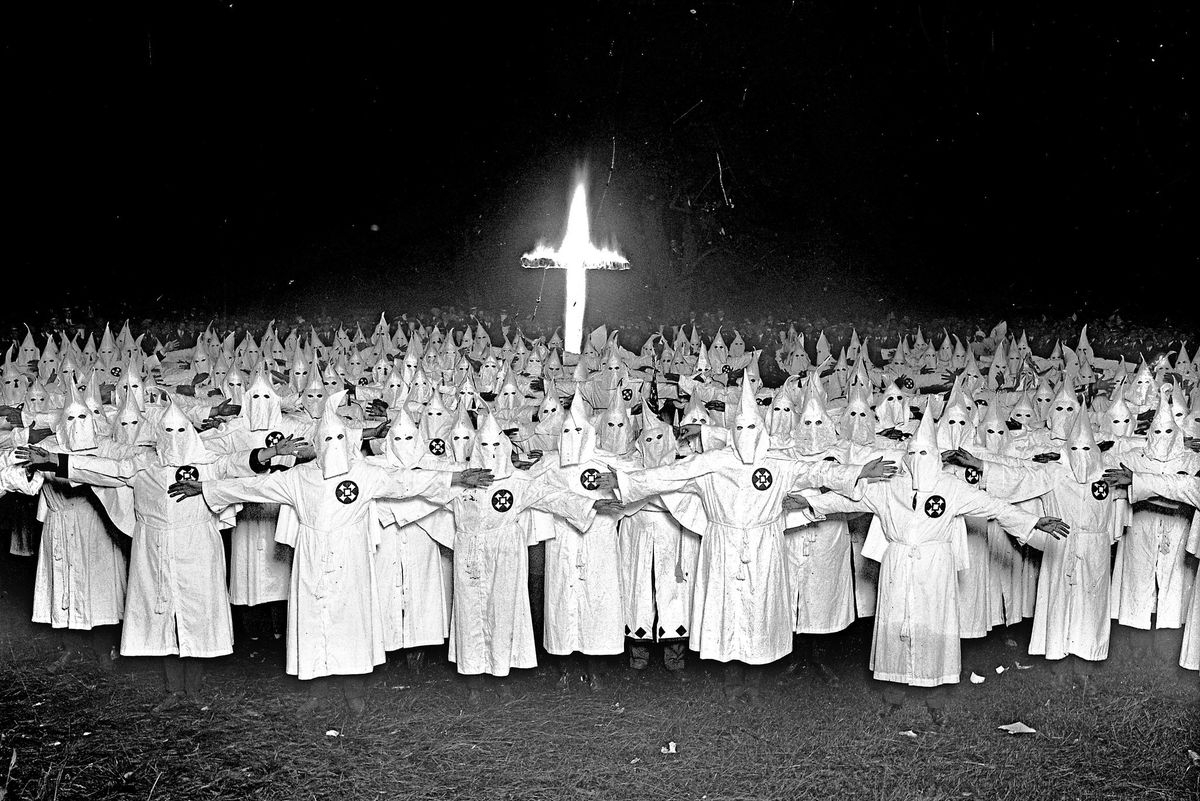 Ku Klux Klan members posing with a burning cross
